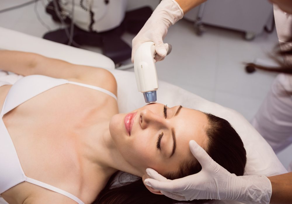 Dermatologist giving facial massage to patient through soniclifting in clinic